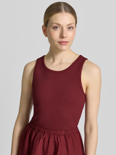 Frauenmodel trägt Fit and Flare Freizeitkleid aus reiner Baumwolle von s.Oliver RED LABEL in dunklem Rot, strukturierte Oberfläche, Nahaufnahme Oberkörper.