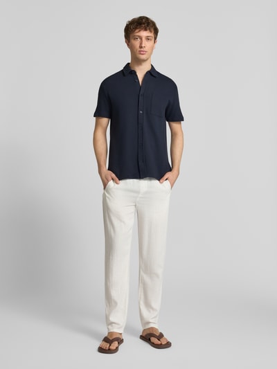 Männermodel trägt Regular Fit Freizeithemd mit Kentkragen Modell 'FILLIP' von Blend aus Reine Baumwolle mit Strukturmuster, Brusttasche, Knopfleiste, navyfarben, Ganzkörperansicht von vorne.