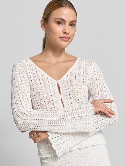 Frauenmodel trägt Cardigan mit V-Ausschnitt und Knopfleiste von Rich & Royal aus Reine Baumwolle, Ajour-Strick, Straight Fit, Trompetenärmel, Nahaufnahme Oberkörper.