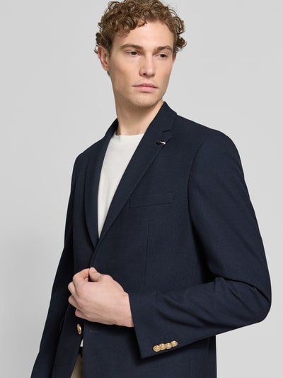 Mężczyzna model nosi Regular Fit 2-Knopf-Sakko mit Pattentaschen von bugatti, materiał z domieszką wiskozy, wzór strukturalny, kołnierz z klapami, patki na kieszeniach, długość tyłu w rozmiarze 50: 74 cm, szerokość w rozmiarze 50: 46 cm, długość rękawa w rozmiarze 50: 66 cm, kolor granatowy, prosty krój, gładka faktura, zbliżenie na górną część ciała, widok z przodu.