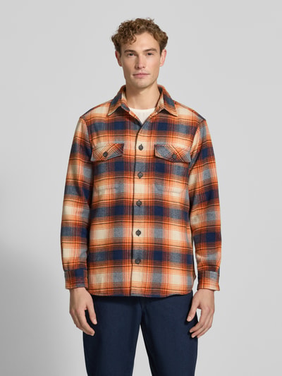 Männermodel trägt Regular Fit Hemdjacke mit Brusttaschen von Christian Berg Men in Orange-Blau kariert, Kentkragen, Ganzkörperansicht von vorne. Rückenlänge 71 cm, Schulterbreite 43 cm, Ärmellänge 68 cm, durchgehende Knopfleiste, der Stoff wirkt weich und strukturiert.