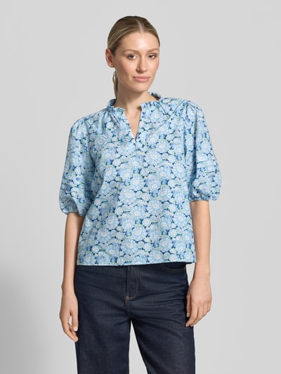 Frauenmodel trägt Bluse mit Serafino-Kragen und Ballonärmeln von Rich & Royal aus Reine Baumwolle, florales Muster in Blau, Loose-Fit, Ganzkörperansicht von vorne.