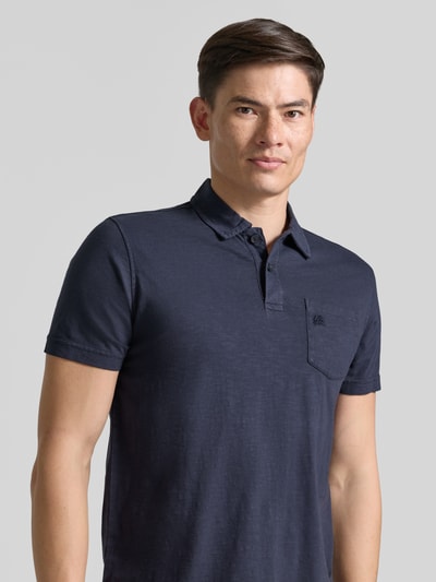 Mężczyznamodel nosi Regular Fit Poloshirt mit Brusttasche od Lerros z bawełny, kołnierzyk polo, krótka listwa guzikowa, brustasza, wyhaftowane logo, długość tyłu w rozmiarze M: 66 cm, ciemnogranatowy, gładka tekstura, prosty krój, Nahaufnahme górnej części ciała.