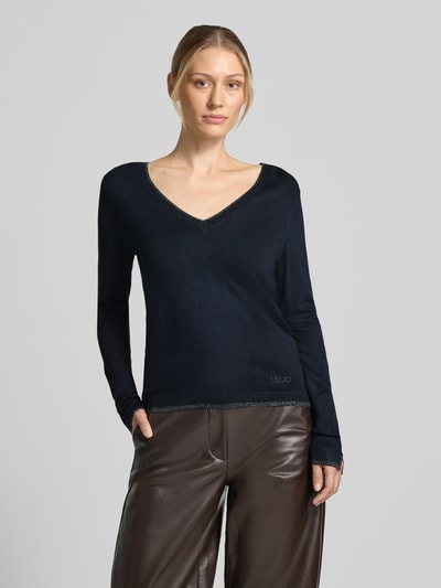Frauenmodel trägt Slim Fit Longsleeve aus reine Viskose Modell 'Maglia Chiusa' von Liu Jo White in Schwarz, V-Ausschnitt, Logo-Detail, Ganzkörperansicht von vorne.