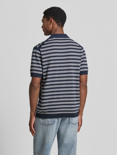 Męski model nosi Regular Fit Poloshirt mit V-Ausschnitt od Christian Berg Men z bawełny, kołnierzyk polo, tył długość 68 cm, rękawy 27 cm, widok całej sylwetki od tyłu