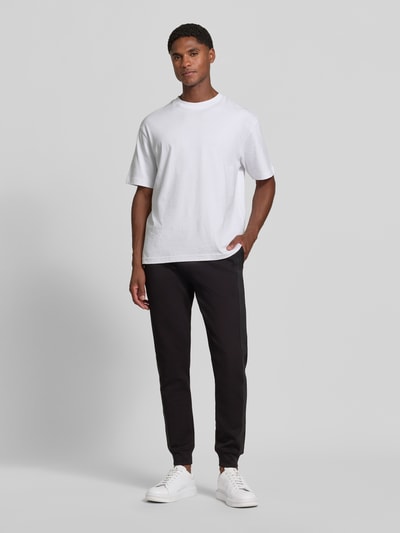 Männermodel trägt Sweatpants mit Bordüre von Armani Exchange in Schwarz, Baumwoll-Mix, gerader Schnitt, Ganzkörperansicht von vorne.