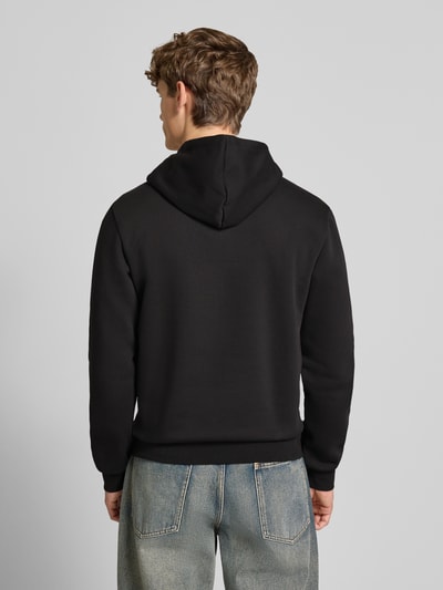Männermodel trägt Hoodie mit Kapuze von adidas Originals in Schwarz, lockerer Schnitt, Baumwoll-Mix, Rückenansicht, Ganzkörperansicht Rückansicht.