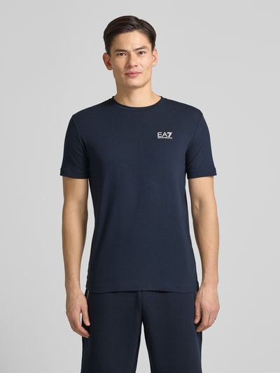 Männermodel draagt T-Shirt met Label-Print van EA7 Emporio Armani, donkerblauw, slim fit, katoenen mix, voorkant, geheellichaamsaanzicht.