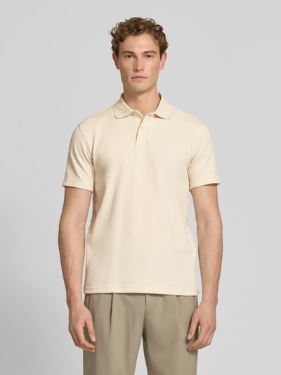 Männermodel trägt Regular Fit Poloshirt aus Baumwoll-Mix Modell 'BLAZE' von SELECTED HOMME in Beige, Struktur Piqué, Ganzkörperansicht von vorne.