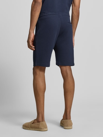 Männermodel trägt Regular Fit Shorts mit Tunnelzug von MCNEAL in Dunkelblau, Baumwoll-Mix mit Stretch-Anteil, Gesäßtasche, Ganzkörperansicht Rückansicht.