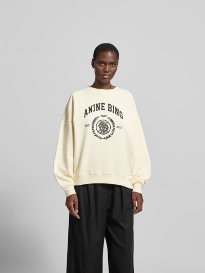 Frauenmodel trägt Oversized Sweatshirt mit Logo-Print von Anine Bing aus Reine Baumwolle, cremefarben, elastische Abschlüsse, Rundhalsausschnitt, Rückenlänge bei Größe S: 61 cm, Ganzkörperansicht von vorne.
