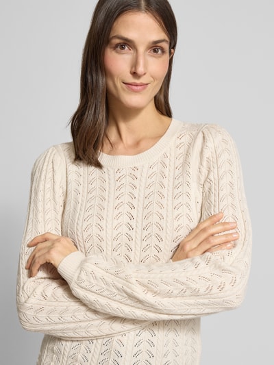 Kobiece modelka nosi Strickpullover mit gerippten Abschlüssen Modell 'Clarry' od FREE/QUENT, kremowy, okrągły dekolt, krój slim fit, dzianina z mieszanki wiskozy, długość tyłu w rozmiarze S: 56 cm, długość rękawa w rozmiarze S: 66 cm, tekstura ażurowa, zbliżenie na górną część ciała.