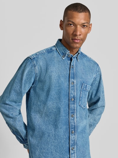 Männermodel trägt Regular Fit Jeansjacke aus reiner Baumwolle Modell 'LAMBEY BO FLEAK' von BOSS Orange, Denim-Optik, Nahaufnahme Oberkörper.