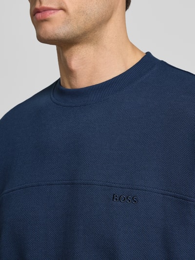 Männermodel trägt Regular Fit T-Shirt aus Baumwoll-Mix Modell 'TE_HIVE' von BOSS Orange, Struktur, unifarben, Label-Detail, Nahaufnahme Oberkörper.