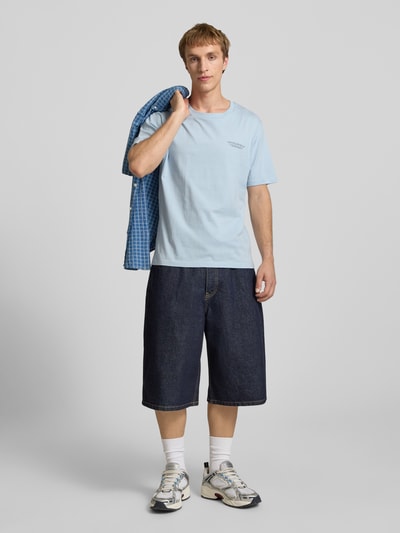 Männermodel trägt T-Shirt mit Label-Print und Rundhalsausschnitt von Jack & Jones in Hellblau, Regular Fit, reine Baumwolle, Ganzkörperansicht von vorne.
