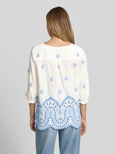 Frauenmodel trägt Relaxed Fit Bluse mit Lochstitching in Paisley-Optik von More & More, weiße und blaue Farben, Baumwoll-Mix, 3/4-Arm, V-Ausschnitt, Rückenlänge 66 cm, Ärmellänge 45 cm, Ganzkörperansicht Rückansicht.