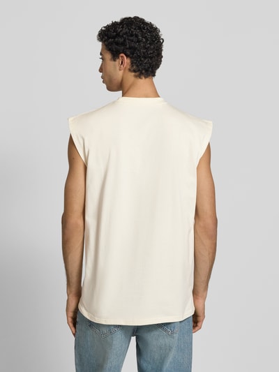 Männermodel trägt T-Shirt mit Label-Stitching von KARL KANI in Beige, Herren T-Shirt aus Reine Baumwolle, Relaxed-Fit, Rückenlänge 74 cm, Ganzkörperansicht Rückansicht.