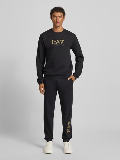 Männermodel trägt Spodnie dresowe mit elastyczny pas i nadruk z logo, krój regular fit, bawełna, EA7 Emporio Armani, długość wewnętrzna nogawki 78 cm, Ganzkörperansicht von vorne.