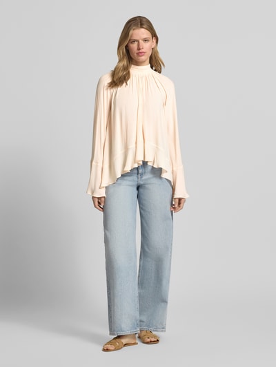 Kobiece model nosi Blusenshirt mit Stehkragen od Gina Tricot, prosty krój, marszczenia, szerokie rękawy, długość tyłu 73 cm, długość rękawów 68 cm, jasne kolory, gładka faktura. Ganzkörperansicht von vorne.