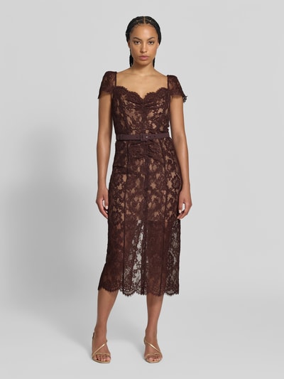 Frauenmodel trägt Midikleid mit Allover-Spitzenbesatz von Self-Portrait in Dunkelbraun, Baumwolle, taillierte Passform, Gürtel, Ganzkörperansicht von vorne.