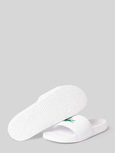 Produktfoto, Badeschuhe mit Logo Print Modell 'SERVE SLIDE' von Lacoste in Weiß, Optik: Unifarben, Schuhspitze: Abgerundet, Absatzform: Flach, Applikation: Logo-Print, Verschluss: Schlupf/offen, strukturierte Sohle