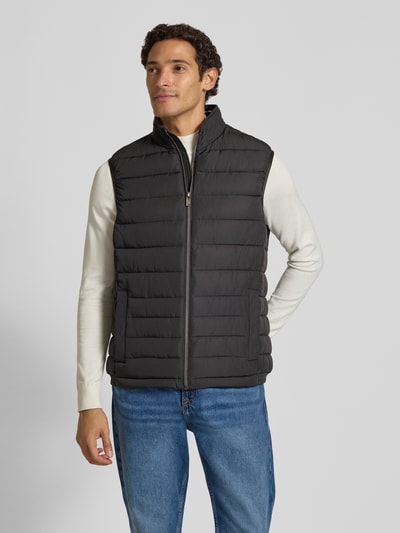 Männermodel trägt Steppweste mit Stehkragen und Eingrifftaschen von Christian Berg Men in Schwarz, Regular Fit, Ganzkörperansicht von vorne