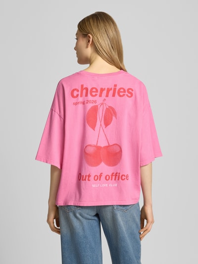 Frauenmodel trägt T-Shirt mit rückseitigem Motiv-Print Modell 'NICA' von ICHI in Pink mit rotem Statement-Print, reine Baumwolle, Loose Fit, Ganzkörperansicht Rückansicht.