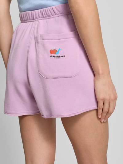Vrouwenmodel draagt lichtroze Sweatshorts met elastische tailleband, rechte fit, achterzak en zijzakken, 'TUBAY' van American Vintage, katoen-elastaanmix, detailopname achterkant.