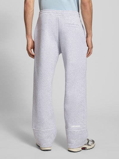 Männermodel trägt Sweatpants mit elastischem Bund und Logo von REVIEW in Hellgrau, Relaxed-Fit, Reine Baumwolle, Ganzkörperansicht Rückansicht.