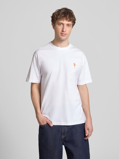 Männermodel trägt Relaxed Fit T-Shirt aus reiner Baumwolle Modell 'FRED' von Only & Sons in Weiß, Label Patch und Motiv-Stitching auf der Brust, kurzarm, Rundhals, Jersey-Textur, unifarben, Ganzkörperansicht von vorne.