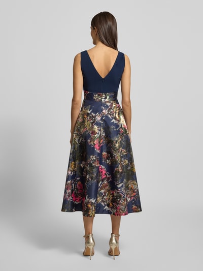 Frauenmodel trägt Abendkleid mit U-Boot-Ausschnitt von Christian Berg Cocktail, Material-Mix mit Stretch-Anteil, florales Muster, taillierter Schnitt, blickdichter Unterrock, Nahtreißverschluss, Rückenlänge 123 cm, Brustweite 41 cm, Ganzkörperansicht Rückansicht.