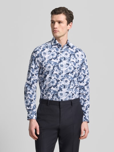 Männermodel trägt Slim Fit Business-Hemd mit Kentkragen und floralem Muster von OLYMP Level Five, Weiß-Blau, Nahaufnahme Oberkörper. Reine Baumwolle, schmale Passform, florales Design, Kentkragen, Rückenlänge 73 cm, Schulterbreite 42 cm, Ärmellänge 67 cm.