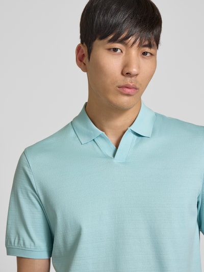 Männermodel trägt Regular Fit Poloshirt mit Strukturmuster von bugatti in Hellblau, Reine Baumwolle, Polokragen, V-Ausschnitt, Nahaufnahme Oberkörper. Rückenlänge bei Größe M: 70 cm, Label-Detail.