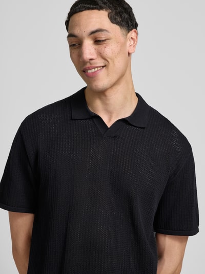 Männermodel trägt schwarzes Strickshirt mit Baumwoll-Anteil Modell 'JERRY' von Jack & Jones, Semitransparente-Optik, Nahaufnahme Oberkörper.