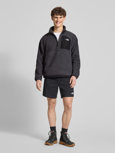 Männermodel trägt Fleecepullover mit Napoleontasche Modell 'YUMIORI' von The North Face, dunkle Farbe, gerade Passform, Ganzkörperansicht von vorne