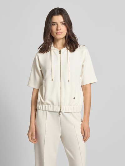 Frauenmodel trägt Sweatjacke mit Halbarm Modell 'Therese' von JOOP! in Creme, Elastischer-Material-Mix, Gerader-Schnitt, Kapuze mit Tunnelzug, Reißverschluss, Halbarm, Label-Detail, Elastischer-Bund, Eingrifftaschen, glatte Textur, Ganzkörperansicht von vorne.