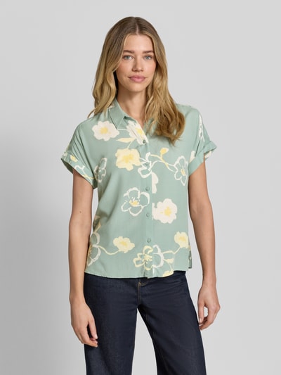 Vrouwenmodel draagt Bluse aus Viskose mit fixiertem Ärmelaufschlag van JAKE*S STUDIO WOMAN in lichtgroen met bloemendessin, recht model, kentkraag, knoopsluiting, korte mouwen met vaste omslag, zuiver viscose, ruglengte maat 36: 62 cm, mouwlengte maat 36: 13 cm, geheel van voren.