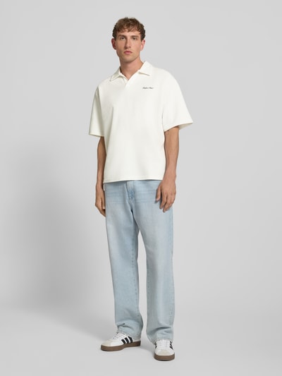Männermodel trägt Regular Fit Poloshirt mit Logo Modell 'Eddie' von Redefined Rebel aus Baumwoll-Mix, V-Ausschnitt, helles Uni-Design, Rückenlänge bei Größe M 73 cm, Ganzkörperansicht von vorne.