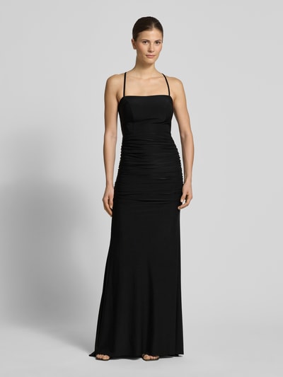 Frauenmodel trägt Abendkleid mit Raffungen und rückseitiger Schnürung von TROYDEN COLLECTION, schwarzes Maxikleid, figurbetont, Spaghettiträger, Ganzkörperansicht von vorne.