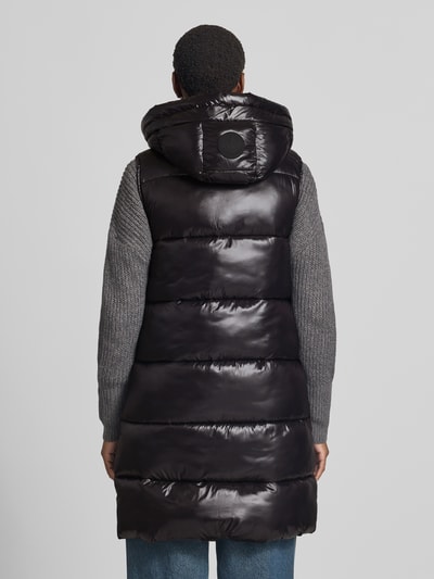 Vrouwenmodel draagt zwarte bodywarmer met tweewegritssluiting van Save The Duck, Model 'IRIA', A-lijn, capuchon met tunnelkoord, ritszakken, ruglengte maat S 92 cm, schouderbreedte 39 cm, borstwijdte 50 cm, glanzende oppervlaktestructuur. Ganzlichaamsaanzicht achterkant.
