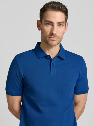 Męski model nosi Regular Fit Poloshirt aus reiner Baumwolle von s.Oliver RED LABEL, kolor jednolity, bawełna, piqué, krótki rękaw, kołnierzyk polo, przód z krótkim zapięciem na guziki, naszywka z logo, dół z rozcięciami po bokach, perspektywa: zbliżenie na górną część ciała.