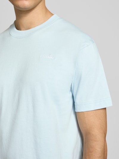 Männermodel trägt hellblaues Herren T-Shirt mit Label-Stitching Modell 'ACCIANO CLASSIC' von Ellesse aus reiner Baumwolle, Nahaufnahme Oberkörper.