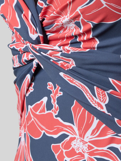 Frauenmodel trägt Badeanzug mit Neckholder Modell 'Camolo' von Barts im Material-Mix mit Stretch-Anteil, florales Muster, Knoten-Detail, Nahaufnahme Oberkörper.