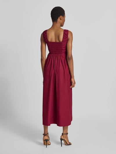 Frauenmodel trägt Cocktailkleid mit Karree-Ausschnitt Modell 'WIMI' von YAS aus reiner Baumwolle in A-Linie und Midilänge, Ganzkörperansicht Rückansicht.