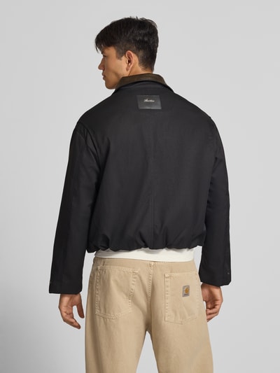 Männermodel trägt schwarze Twill Jacke mit Label- und Motiv-Stitching von ANOTHER COTTON LAB, glatte Oberfläche, Ganzkörperansicht Rückansicht.