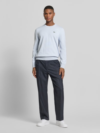 Männermodel trägt Regular Fit Strickpullover aus Baumwoll-Mix von Lacoste in Optik: Unifarben mit Logo-Stitching, Ganzkörperansicht von vorne.