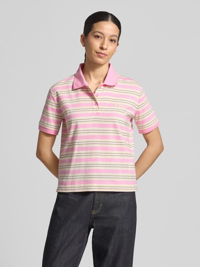 Modelka kobieca ma na sobie koszulkę polo Regular Fit Poloshirt aus reiner Baumwolle Modell 'MANDARE' od MAX&Co, efekt: wielokolorowe paski, aplikacja z logo, kołnierzyk polo, dekolt w serek, zapięcie na ukrytą listwę guzikową, krótki rękaw z prążkowanym zakończeniem, wykończenie korpusu z rozcięciami po bokach, drobne prążkowanie, materiał: czysta bawełna; widok całej sylwetki z przodu.