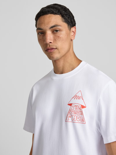 Mannelijk model draagt witte T-shirt met motiefprint model 'MOUNTAIN PLAY' van The North Face van puur katoen, regular fit, ronde hals, logoprint op achterkant, ruglengte maat M 71 cm, detailopname bovenlichaam.