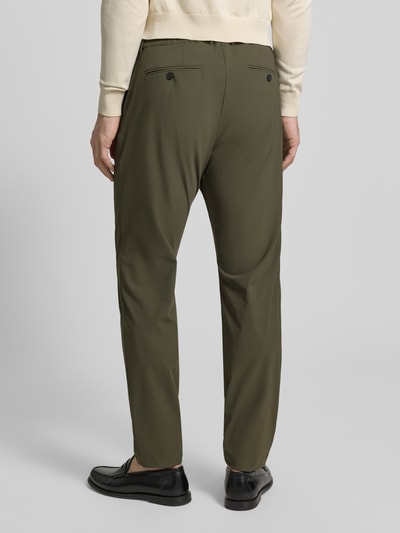 Męski model nosi Slim Fit Hose mit Paspeltaschen am Gesäß von CRUNA w kolorze oliwkowym, materiał z domieszką stretchu, krój slim fit, kieszenie skośne, pas z tyłu, Szerokość w rozmiarze 50: 44 cm, długość wewnętrzna nogawki: 73 cm, widok całej sylwetki od tyłu.