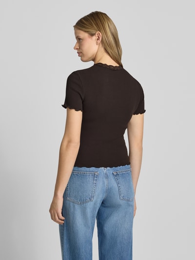 Modelka kobieca ma na sobie Slim Fit T-Shirt aus Baumwoll-Mix Modell 'VINI' od Only, brązowy, gładki, krój slim fit, koronkowa aplikacja, okrągły dekolt, krótkie rękawy z falowanym brzegiem, materiał prążkowany, bawełniany miks, widok całej sylwetki z tyłu.